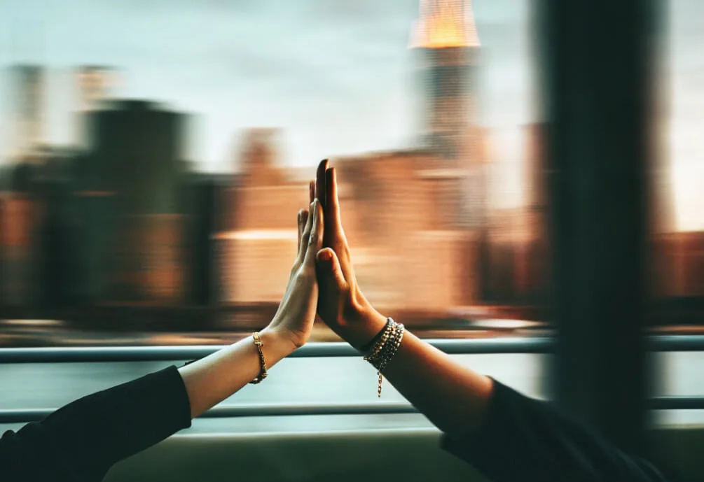 Two hands high-fiving in front of the New York skyline